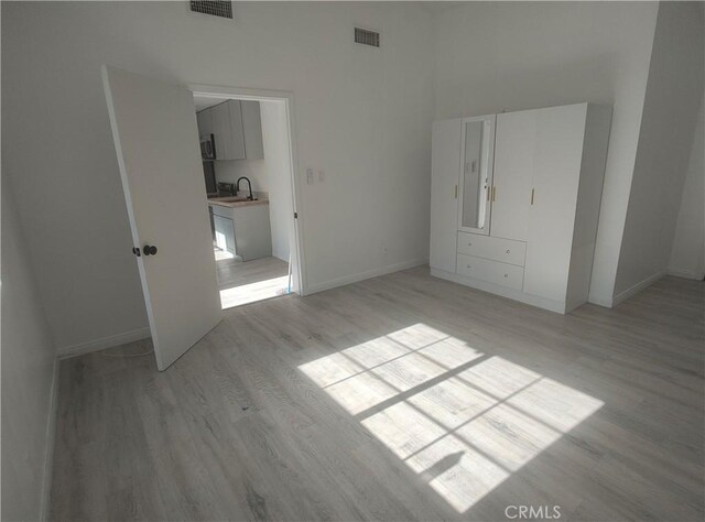 7716 Owensmouth Ave, Canoga Park, CA 91304 - unfurnished bedroom with light wood-type flooring, baseboards, a sink, and a high ceiling