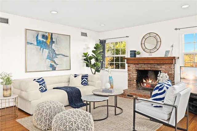 living room with a brick fireplace and hardwood / wood-style floors