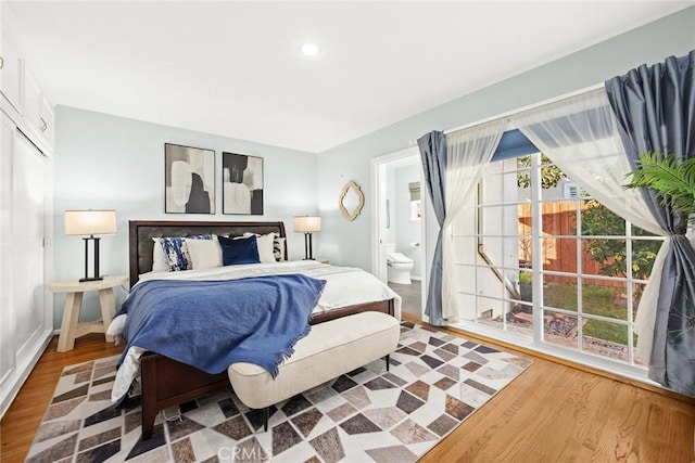 bedroom with connected bathroom and hardwood / wood-style floors