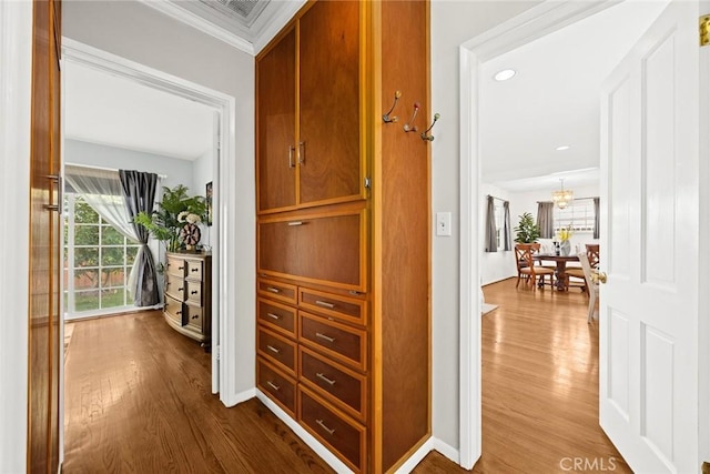 hall with hardwood / wood-style floors, ornamental molding, and a chandelier