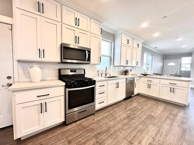 kitchen with tasteful backsplash, light hardwood / wood-style floors, kitchen peninsula, sink, and stainless steel appliances