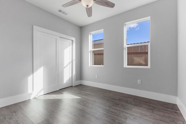 unfurnished bedroom with a ceiling fan, wood finished floors, visible vents, and baseboards