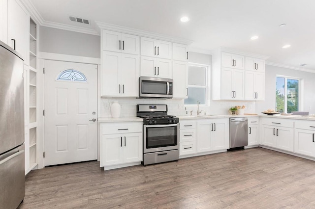 kitchen with visible vents, a sink, appliances with stainless steel finishes, crown molding, and light countertops