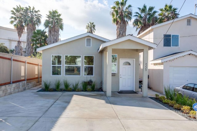 view of front of property featuring concrete driveway, fence, and stucco siding