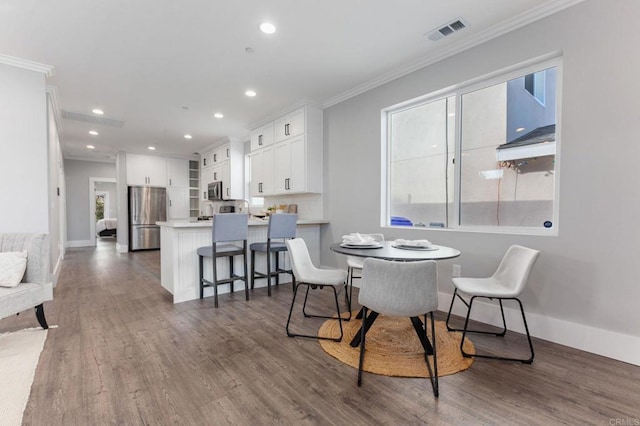 dining space featuring recessed lighting, visible vents, dark wood-type flooring, and ornamental molding