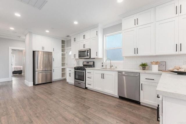 kitchen featuring a sink, stainless steel appliances, wood finished floors, and crown molding