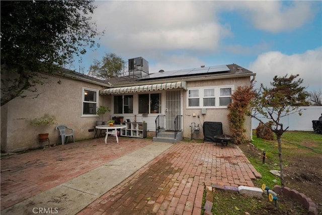 back of property featuring central AC unit, a patio area, and solar panels