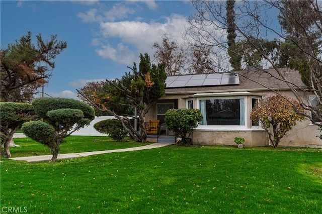 view of front facade with a front yard and solar panels