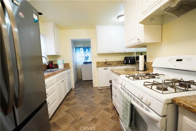 kitchen featuring stone finish flooring, white cabinetry, under cabinet range hood, washer / dryer, and white appliances