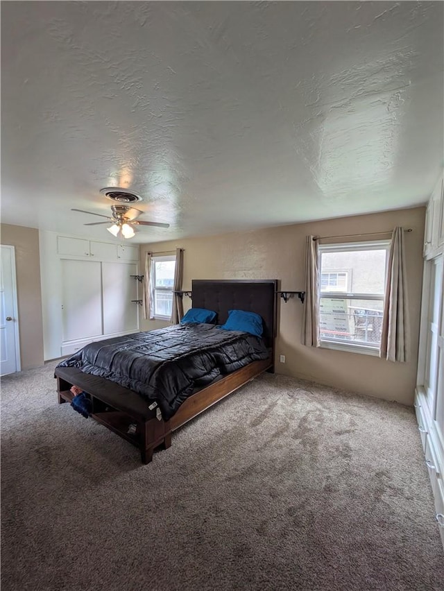 unfurnished bedroom featuring carpet floors, a textured ceiling, multiple windows, and visible vents