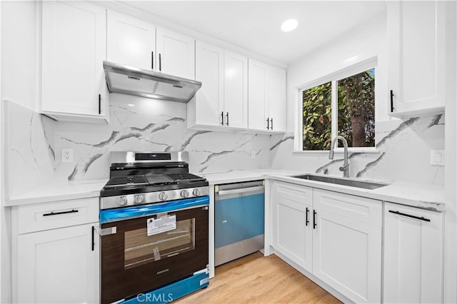 kitchen featuring white cabinets, appliances with stainless steel finishes, sink, backsplash, and light hardwood / wood-style flooring