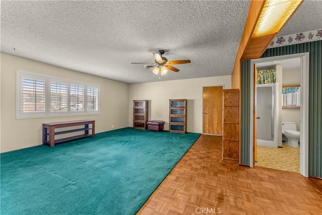 interior space featuring ceiling fan, light parquet flooring, and a textured ceiling