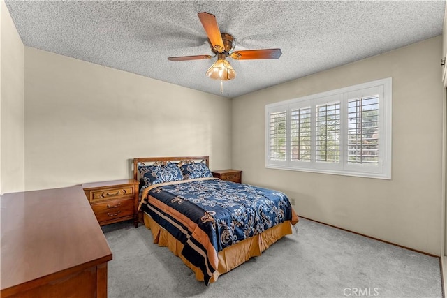 carpeted bedroom featuring ceiling fan and a textured ceiling