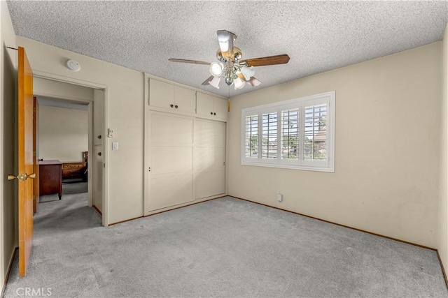 unfurnished bedroom featuring light carpet, ceiling fan, a closet, and a textured ceiling