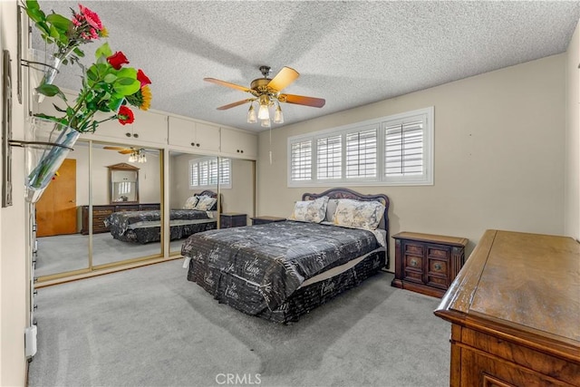 carpeted bedroom with ceiling fan, a textured ceiling, and a closet