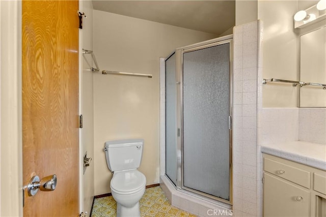 bathroom featuring toilet, vanity, and a shower with door