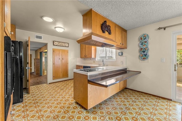 kitchen featuring kitchen peninsula, a kitchen bar, sink, electric cooktop, and a textured ceiling