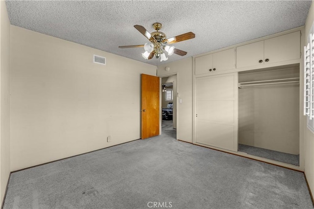 unfurnished bedroom with a textured ceiling, ceiling fan, a closet, and light colored carpet