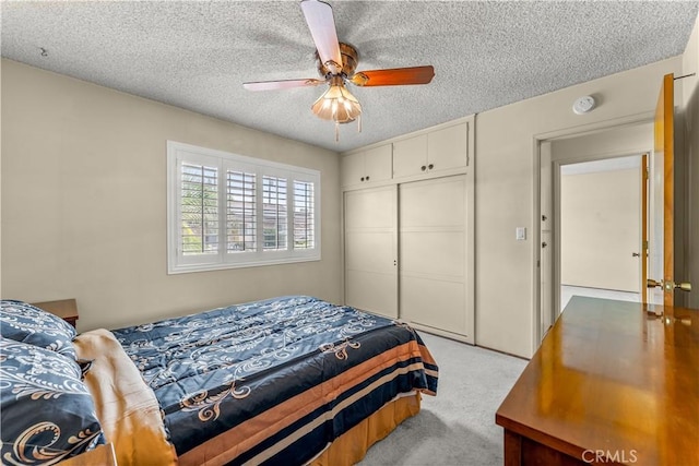 carpeted bedroom featuring ceiling fan, a textured ceiling, and a closet