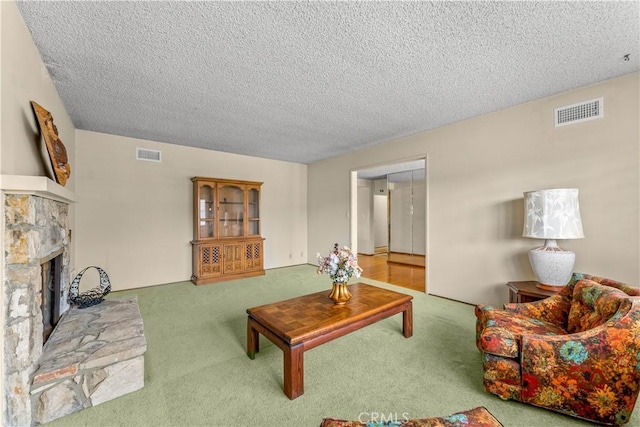 carpeted living room featuring a fireplace and a textured ceiling