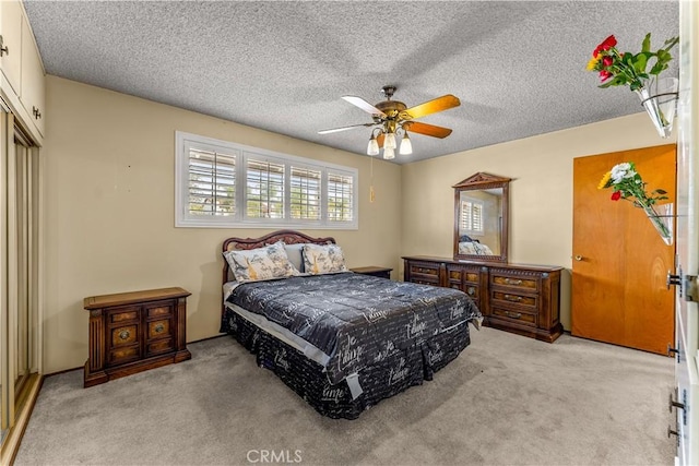 bedroom with ceiling fan, a textured ceiling, and light carpet