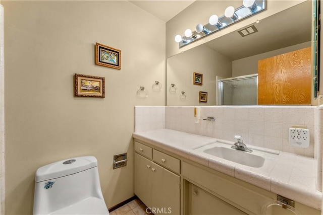 bathroom featuring tasteful backsplash, vanity, tile patterned flooring, toilet, and a shower with door