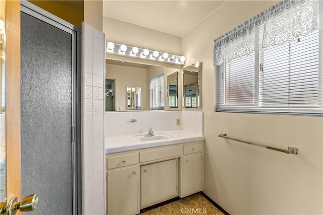 bathroom with a shower with shower door and vanity