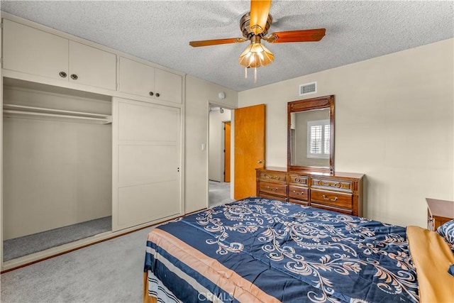 carpeted bedroom featuring a textured ceiling, ceiling fan, and a closet