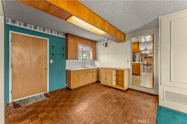 kitchen with ceiling fan, sink, a textured ceiling, and dark parquet floors