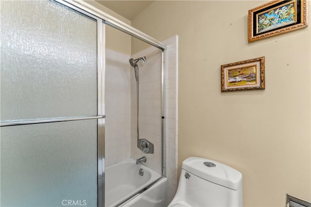 bathroom featuring toilet and shower / bath combination with glass door