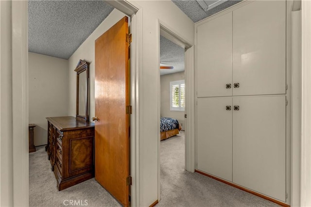 corridor featuring light colored carpet and a textured ceiling