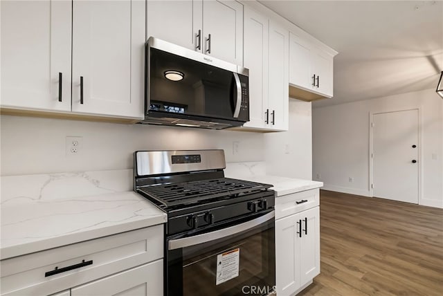 kitchen featuring wood-type flooring, light stone countertops, white cabinetry, and stainless steel appliances