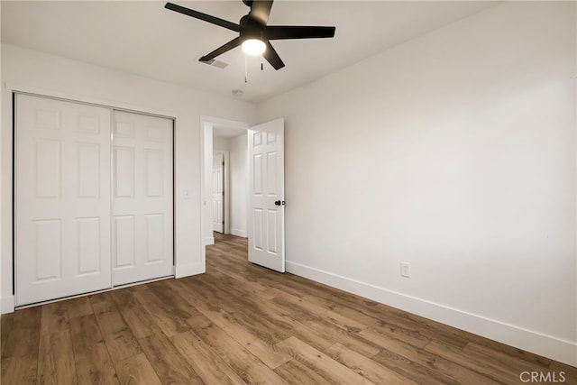 unfurnished bedroom featuring ceiling fan, wood-type flooring, and a closet