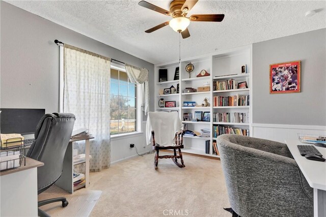 home office featuring ceiling fan, built in shelves, light carpet, and a textured ceiling