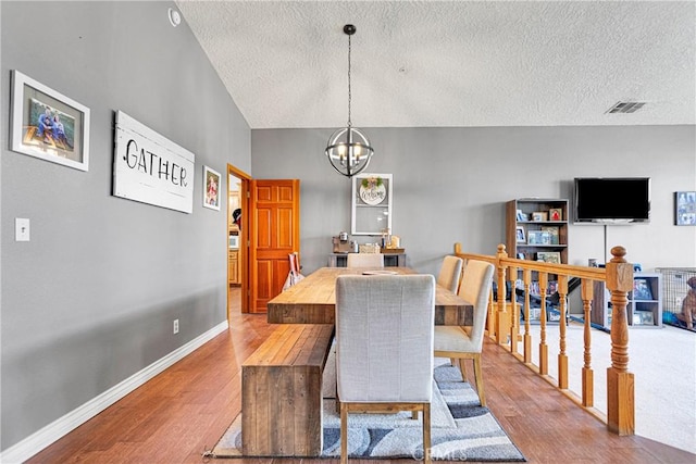 dining area with light hardwood / wood-style floors, a textured ceiling, and a notable chandelier