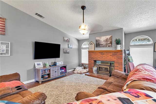 living room featuring a textured ceiling, a brick fireplace, vaulted ceiling, and wood-type flooring