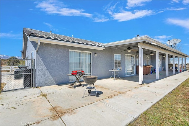 rear view of property featuring ceiling fan and a patio area