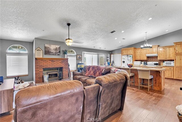 10187 Mesquite St, Oak Hills, CA 92344 - living room with light wood-style flooring, a textured ceiling, a fireplace, ceiling fan, and lofted ceiling