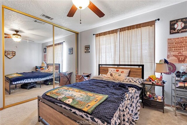 carpeted bedroom with a textured ceiling, ceiling fan, and a closet