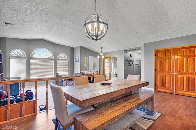 10187 Mesquite St, Oak Hills, CA 92344 - dining area featuring vaulted ceiling, wood finished floors, a chandelier, and a textured ceiling