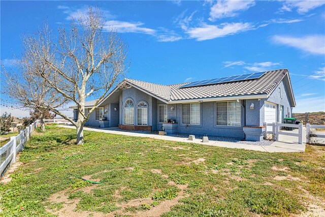 single story home with a front lawn, solar panels, and a garage