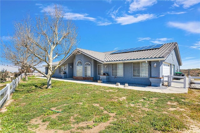 10187 Mesquite St, Oak Hills, CA 92344 - rear view of house featuring an attached garage, roof mounted solar panels, stucco siding, and a tile roof