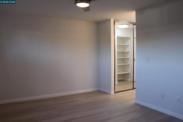 empty room with ceiling fan, hardwood / wood-style floors, and built in features