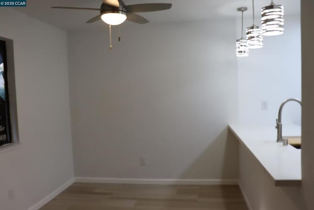 empty room featuring sink, wood-type flooring, and ceiling fan