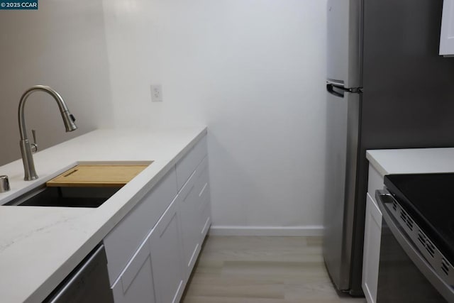 kitchen with light stone countertops, sink, white cabinets, and black dishwasher