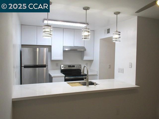 kitchen with white cabinets, appliances with stainless steel finishes, sink, hanging light fixtures, and kitchen peninsula