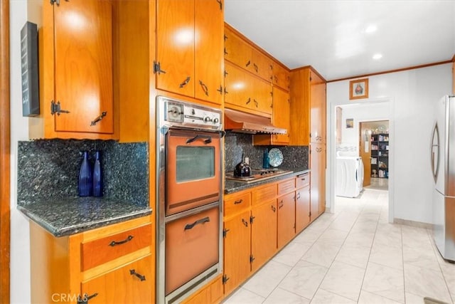 kitchen with washer / clothes dryer, backsplash, oven, stainless steel refrigerator, and gas cooktop