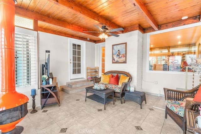 living area featuring wood ceiling, ceiling fan, and beamed ceiling