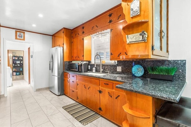 kitchen featuring decorative backsplash, sink, stainless steel refrigerator, ornamental molding, and dark stone counters