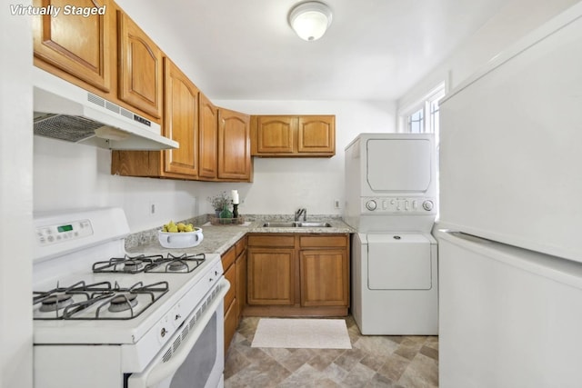 kitchen featuring sink, stacked washer / dryer, and white appliances